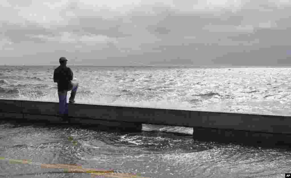 A fisherman takes advantage of the high tide and rising waves to try his hand at fishing from the seawall along Beach Boulevard in Waveland, Miss., as Tropical Storm Isaac's winds begin to hit the Mississippi Gulf Coast, Aug. 28, 2012. 