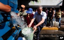 People collect water from a truck that delivers water during rolling blackouts, in Caracas, Venezuela, March 12, 2019.