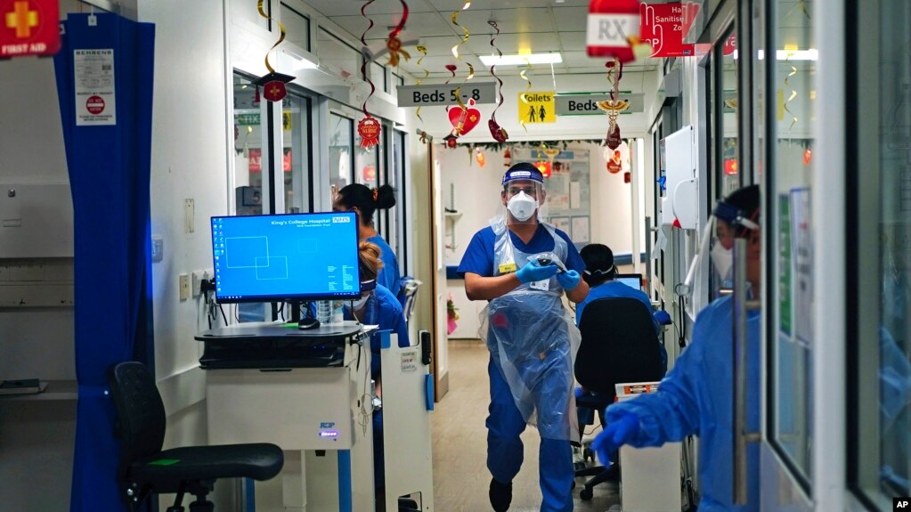 Medical staff wearing PPE, on a ward for COVID-19 patients at King's College Hospital, in south east London, Tuesday, Dec. 21, 2021. (Victoria Jones/PA via AP)