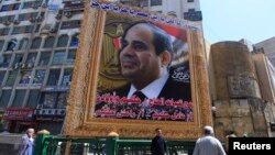 People stand under a huge banner of Egypt's former army chief Abdel Fattah al-Sisi in downtown Cairo, March 27, 2014. 