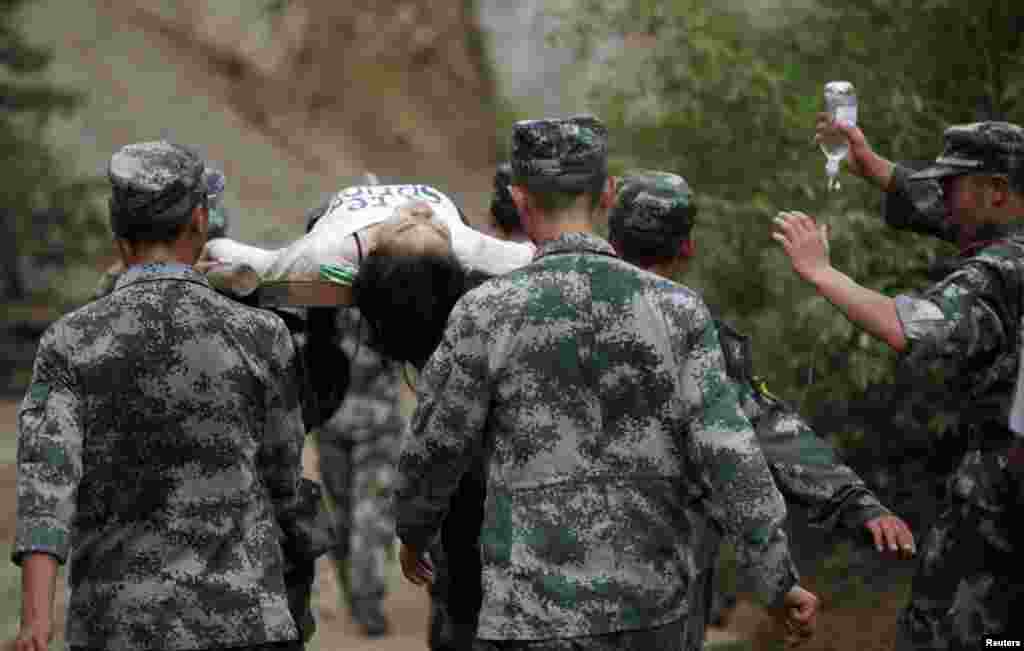 Paramilitary policemen carry an injured woman with a stretcher after an earthquake hit Ludian county of Zhaotong, Yunnan province, August 3, 2014. 