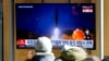 People watch a TV screen showing a news program reporting about North Korea's missile launch with an image at a train station in Seoul, South Korea, Jan. 12, 2022.
