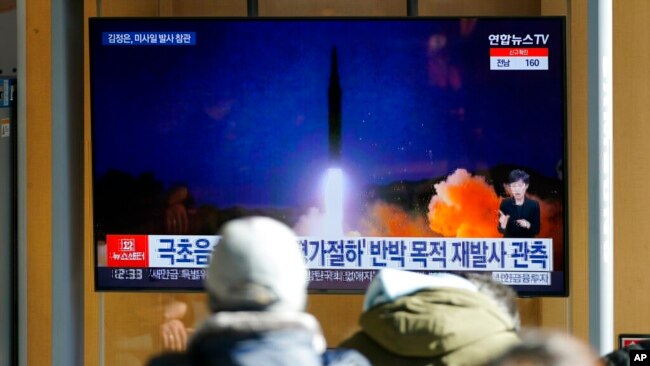 People watch a TV screen showing a news program reporting about North Korea's missile launch with an image at a train station in Seoul, South Korea, Jan. 12, 2022.