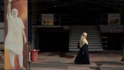 FILE - A Muslim woman walks past an image of Prime Minister Narendra Modi displayed outside an office of the Bharatiya Janata Party in Kochi, Kerala state, India, March 26, 2021..