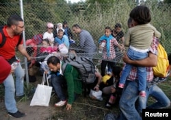 Migrants pass under highway security fence as they try to find a new way to enter Hungary after Hungarian police sealed the border with Serbia near the village of Horgos, Serbia, Sept. 14, 2015, near the Hungarian migrant collection point in Roszke.