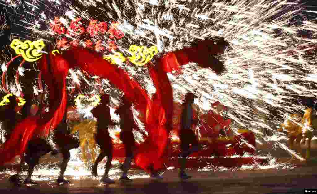Dancers perform a fire dragon dance in the shower of molten iron spewing firework-like sparks during a folk art performance at the Happy Valley amusement park in Beijing, China, to celebrate the traditional Chinese Spring Festival on the first day of the Chinese Lunar New Year, which welcomes the Year of the Horse.