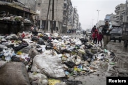 A family crosses a street piled with rubbish in Aleppo, Syria, January 5, 2013.