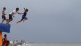 Boys jump into the water despite strong waves after a strong downpour at Manila&#39;s bay, Philippines.