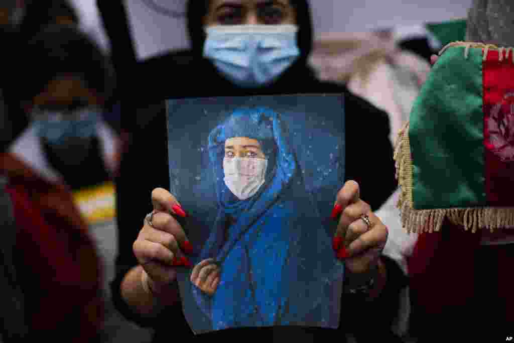 A woman holds a picture during a protest to raise awareness about the situation in Afghanistan, outside European Union headquarters in Brussels, Belgium.