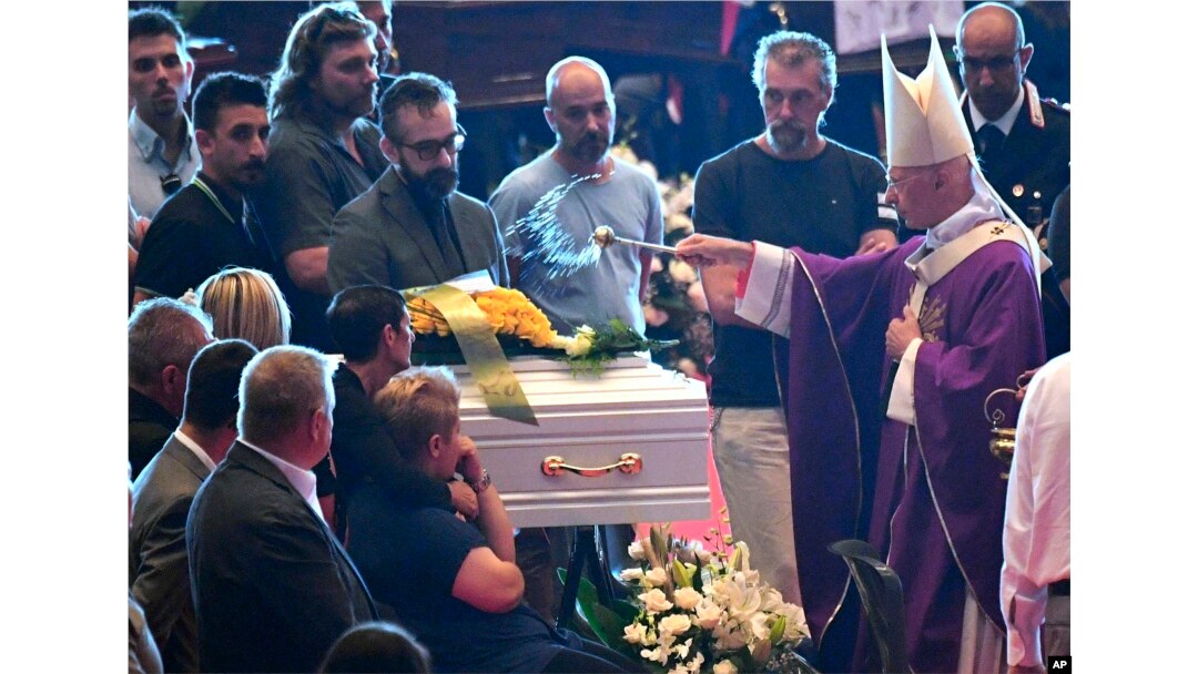 Cardinal Angelo Bagnasco blesses the coffin of nine-year-old Samuel Robbiano during a funeral service for some of the victims of a collapsed highway bridge, in Genoa's exhibition center Fiera di Genova, Italy, Aug. 18, 2018.