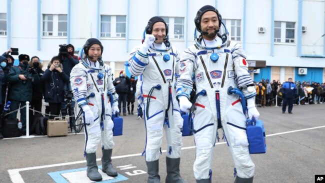 In this photo released by the Roscosmos Space Agency, Roscosmos cosmonaut Alexander Misurkin, center, and spaceflight participants Yusaku Maezawa, left, and Yozo Hirano, right, of Japan, members of the main crew of the new Soyuz mission to the International Space Station (ISS) walk prior to the launch at the Russian leased Baikonur cosmodrome, Kazakhstan, Wednesday, Dec. 8, 2021. (Pavel Kassin/Roscosmos Space Agency via AP)