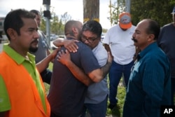 Jesus Gonzales, center left, who has been separated with his wife since Wednesday's shooting, is comforted by local church members including Jose Gomez, center right, in San Bernardino, Calif., Dec. 3, 2015.