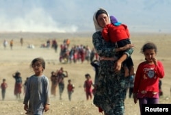 ຊົນກຸ່ມນ້ອຍ ຊາວ Yazidi ທີ່ພາກັນອົບພະຍົບລົບໄພຈາກຄວາມຮຸນແຮງ ຂອງກອງກຳລັງກຸ່ມລັດອິສລາມ ໃນເມືອງ Sinjar, Iraqi Kurdistan, ພາກັນເດີນທາງ ໄປສູ່ ເມືອງຊາຍແດນ Elierbeh, ຊີເຣຍ ທີ່ປົກຄອງໂດຍ Al-Hasakah, 11 ສິງຫາ 2014.
