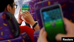 Passengers play the augmented reality mobile game "Pokemon Go" by Nintendo inside a bus in Hong Kong, China, Aug. 12, 2016. 