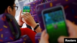 FILE - Passengers play the augmented reality mobile game "Pokemon Go" by Nintendo inside a bus in Hong Kong, China, Aug. 12, 2016. 