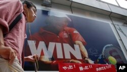 A man walks in front of a sporting goods store with a huge advertisement board showing Japan's tennis player Kei Nishikori, in Tokyo, Sunday, Sept. 7, 2014. 