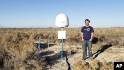 This undated photo provided by Caltech shows radio astronomer Christopher Bochenek with a STARE2 station he developed near the city of Delta, Utah.  (Caltech via AP)