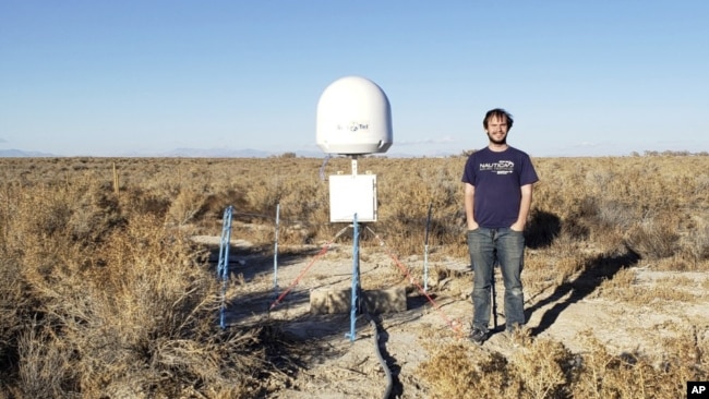 This undated photo provided by Caltech shows radio astronomer Christopher Bochenek with a STARE2 station he developed near the town of Delta, Utah. (Caltech via AP)