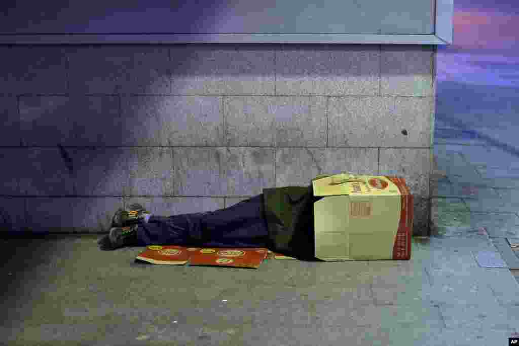 A man sleeps inside a cardboard box in Madrid, Spain. The unemployment rate for the July-September period fell from 26.3 percent to 26.0 percent.