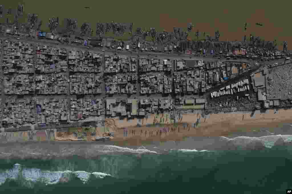 In this drone image, houses lay between the Senegal river, top, and the Atlantic Ocean beach that has been affected by erosion in Saint Louis, Senegal.