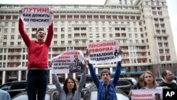 FILE - Russian hold placards during a protest against plans to raise the retirement age and reform the current pension system, in front of the Russian State Duma, the lower house of the Russian Parliament, in Moscow, Russia, July 19, 2018. 