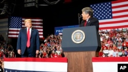 FILE - President Donald Trump listens to Fox News' Sean Hannity speak during a rally at the Show Me Center in Cape Girardeau, Mo., Nov. 5, 2018.