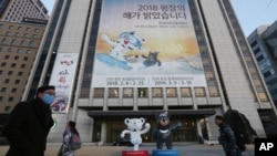 People pass a banner promoting the upcoming 2018 Pyeongchang Winter Olympic as official mascots, a white tiger 'Soohorang' for the Olympic, and the Asiatic black bear "Bandabi" for the Paralympic (Bottom-R) are displayed in downtown in Seoul, South Korea,