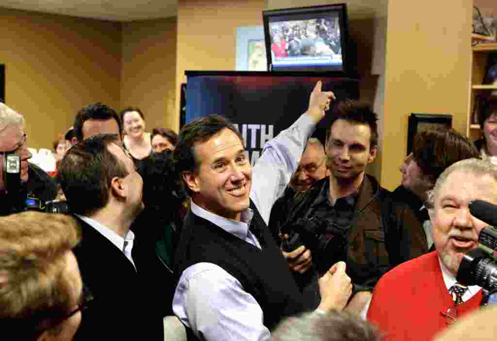 Rick Santorum menunjuk ke layar televisi yang menayangkan kampanyenya secara langsung dari kafe Daily Grind, 1 Januari, di Sioux City, Iowa (AP).