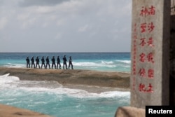 FILE - Soldiers of China's People's Liberation Army (PLA) Navy patrol near a sign in the Spratly Islands, known in China as the Nansha Islands, Feb. 9, 2016.