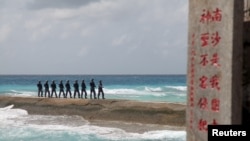 FILE - Soldiers of China's People's Liberation Army (PLA) Navy patrol near a sign in the Spratly Islands, known in China as the Nansha Islands, Feb. 9, 2016. The sign reads "Nansha is our national land, sacred and inviolable."