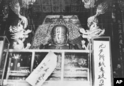 FILE - In this file photo taken Aug. 27, 1966, a Buddha statue is covered with signs reading "Destroy the old world," and "Establish a new world," by ultra-patriotic Red Guard who reject ancient Chinese traditions at Lin Yin temple in Hangzhou, China.