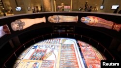 Visitors wearing masks against COVID-19 watch a large display of mummies at the National Museum of Egyptian Civilization in Cairo, Egypt May 29, 2021.