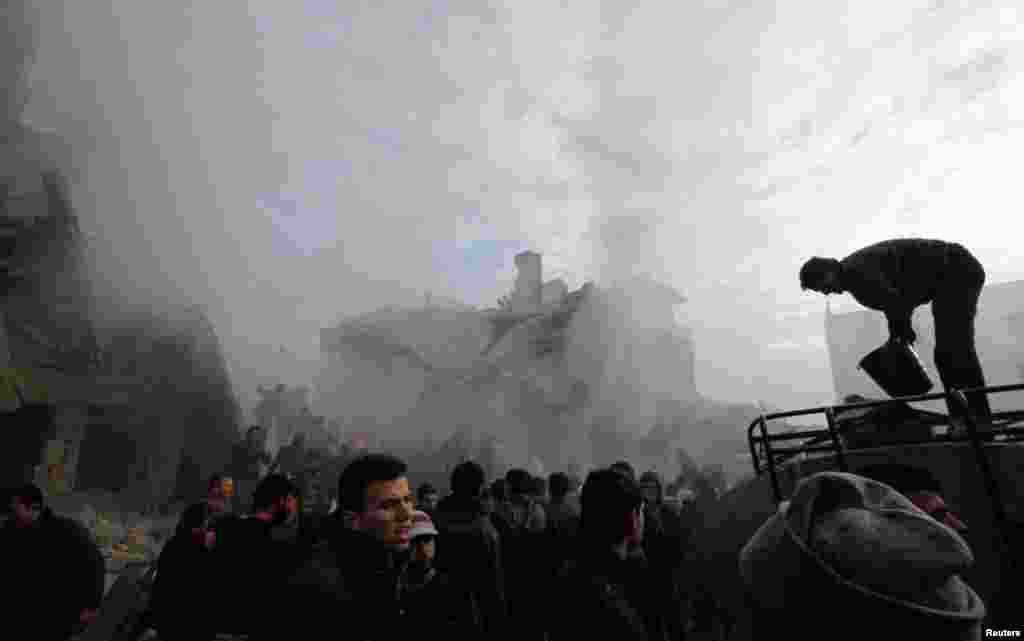 People gather at a site hit by missiles fired by a Syrian Air Force fighter jet in Azaz, north of Aleppo, January 13, 2013.