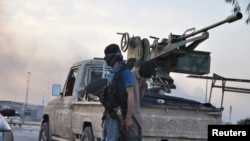 ພວກນັກລົບ ຂອງກຸ່ມອິສລາມຫົວຮຸນແຮງ ISIL ຢືນຍາມ ທີ່ດ່ານກວດແຫ່ງນຶ່ງ ໃນເມືອງ Mosul ທາງພາກເໜືອອີຣັກ (11 ມິຖຸນາ 2014)