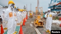Members of a Fukushima prefecture panel, which monitors safe decommissioning of the nuclear plant, inspect the construction site of the shore barrier at the tsunami-crippled Fukushima Daiichi nuclear power plant in Fukushima, in this photo released by Kyo