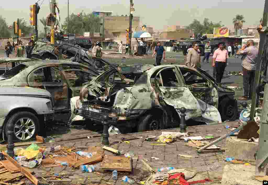 Civilians observe the damage caused by a car bomb in the commercial area of New Baghdad, Iraq, Aug. 26, 2014.