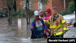 Nhân viên cứu hộ giúp cư dân lội qua chỗ nước ngập vì mưa to ở Baton Rouge, Louisiana, ngày 12 tháng 8 năm 2016.