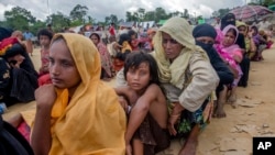 FILE - Rohingya Muslims, who recently crossed over from Myanmar into Bangladesh, wait for their turn to receive food aid near Balukhali refugee camp, Bangladesh, Friday, Sept. 15, 2017. 