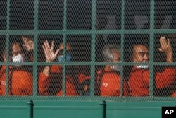 Cambodian prisoners on a prisoner truck arrive at the Phnom Penh Municipal Court in Phnom Penh, Cambodia, Wednesday, Nov. 17, 2021. A court in Cambodia on Wednesday turned down a request for the release on bail of more than a dozen members of a dissolved opposition party charged with treason for taking part in nonviolent political activities over the past several years. (AP Photo/Heng Sinith)