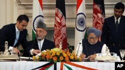 Indian PM Manmohan Singh (R) and Afghanistan President Hamid Karzai, sign agreements during a meeting in New Delhi, Oct. 4, 2011