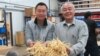 Will Hsu, left, and father Paul Hsu check out some ginseng at their processing center in north-central Wisconsin. (C. Guensburg/VOA)
