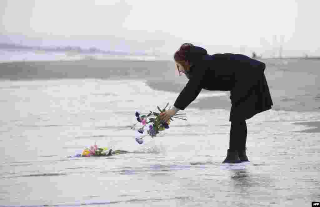 A woman puts flowers into the sea to pray for victims of the 2011 earthquake and tsunami in Sendai, northern Japan. Japan marked the fifth anniversary of the disaster that claimed some 18,500 lives, flattened coastal communities and set off the worst nuclear crisis in a generation.