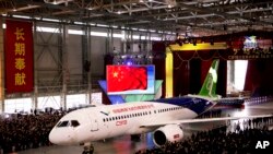 Pesawat penunmpang jet C919 dengan kapasitas 158 kursi buatan The Commercial Aircraft Corp. of China (COMAC) terlihat dikeluarkan dari hangar dalam sebuah upacara di bandara internasional Pudong di Shanghai, China, 2 November 2015 (Foto: dok/AP). Pesawat jet penumpang yang pertama diproduksi China ini akan memulai penerbangan perdananya dalam kuartal pertama tahun ini. 