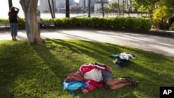 Seorang pria tunawisma tidur di rumput dekat Pantai Waikiki, Honolulu. (Foto: Dok)