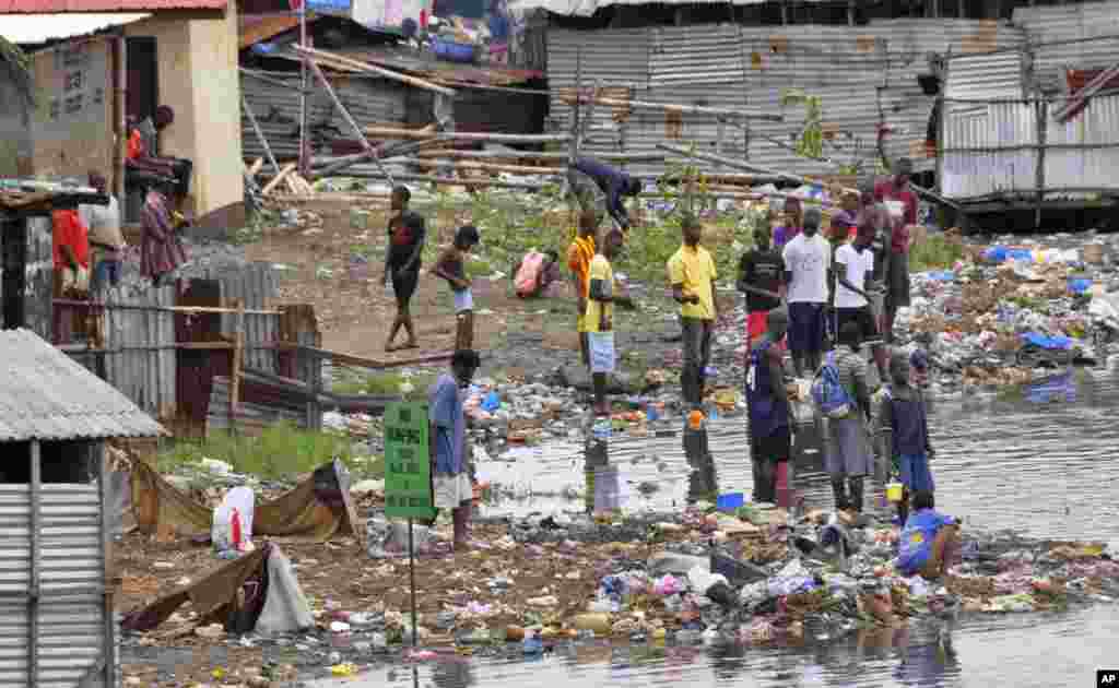 People stand on the shoreline at West Point, Monrovia, Liberia, Aug. 27, 2014.