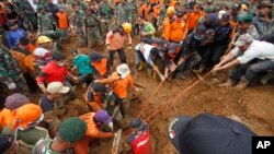 Recovery workers try to extricate the body of a victim of last week's landslide in Jemblung, Indonesia, Dec. 14, 2014
