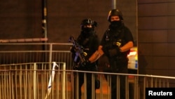 Armed police officers stand next to a police cordon outside the Manchester Arena, where U.S. singer Ariana Grande had been performing, in Manchester, northern England, Britain, May 23, 2017. 