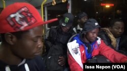 Des migrants, à bord d’un bus, sont conduits vers la salle des formalités, à Ouagadougou, 12 janvier 2018. (VOA/ Issa Napon)