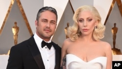 Lady Gaga dan tunangannya, aktor Taylor Kinney, di Dolby Theatre di Los Angeles menjelang acara Academy Awards (28/2). (AP/Invision/Jordan Strauss)