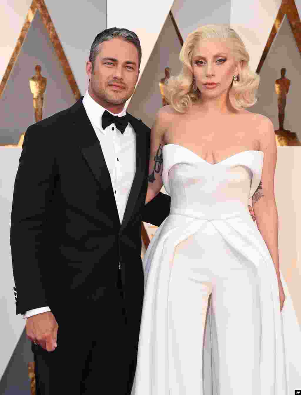 Taylor Kinney, left, and Lady Gaga arrive at the Oscars on Feb. 28, 2016, at the Dolby Theatre in Los Angeles. 